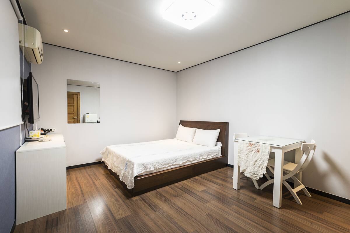 A bedroom with a bed, a desk, and a chair.