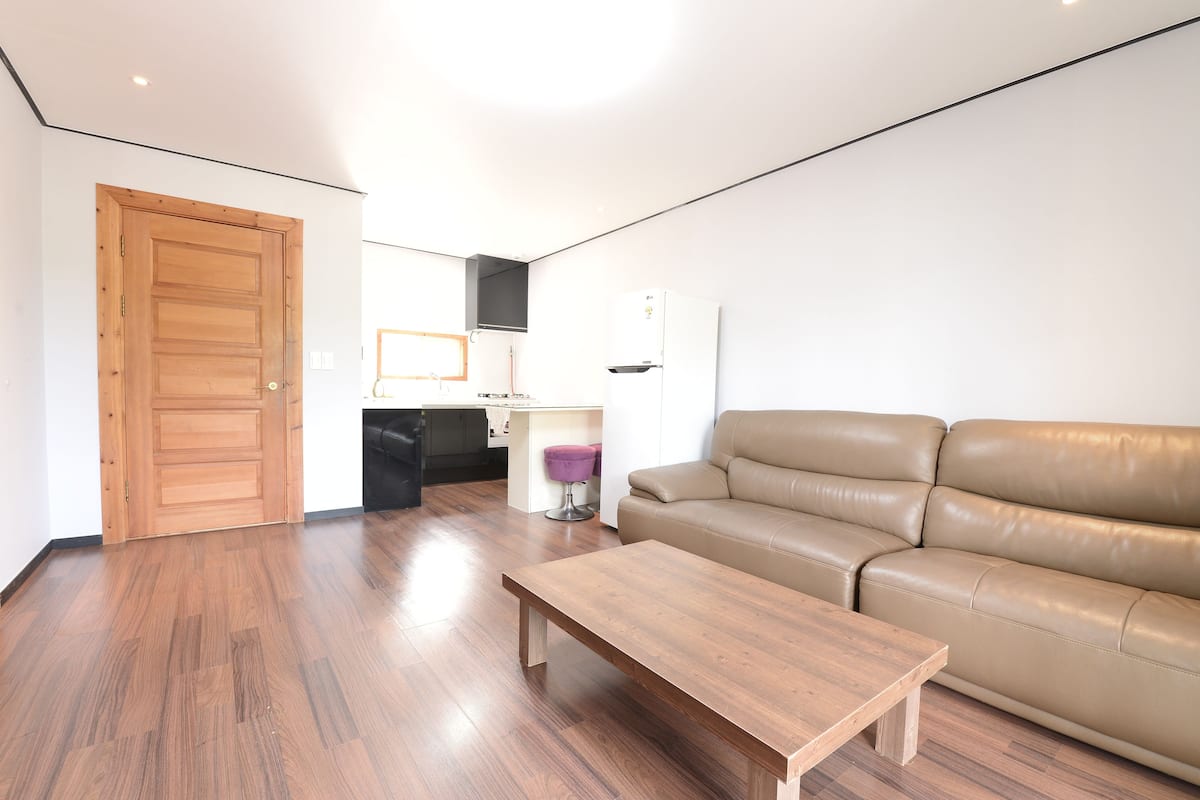 A living room with a wooden floor, a beige sofa, and a wooden coffee table.