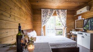 Une pièce de style cabane en bois, avec un lit, une table sur laquelle se trouvent une bouteille et un verre, et un téléviseur fixé au mur.