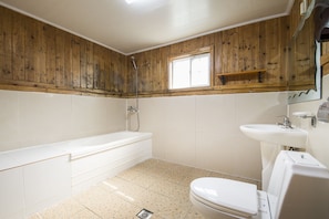 A bathroom with a wooden wall, a bathtub, a toilet, and a sink.