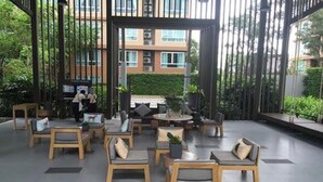 Un vaste espace extérieur aménagé avec des meubles en bois et des plantes en pot, offrant une vue sur un bâtiment doté de grandes fenêtres.
