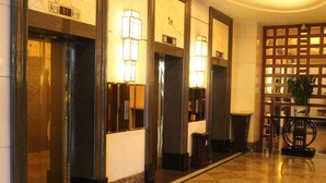 A hotel lobby with a marble floor, elevator doors, and wall-mounted light fixtures. - Dongguan Huihua International Hotel (Dongguan)