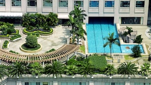 A hotel with a swimming pool, palm trees, and a landscaped garden. - Dongguan Huihua International Hotel (Dongguan)
