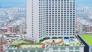 A high-rise hotel with a modern design, featuring a prominent logo on the top. - Dongguan Huihua International Hotel (Dongguan)