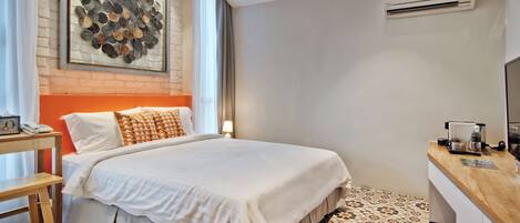 A hotel room with a bed, a desk, a wall-mounted air conditioner, and a patterned floor.