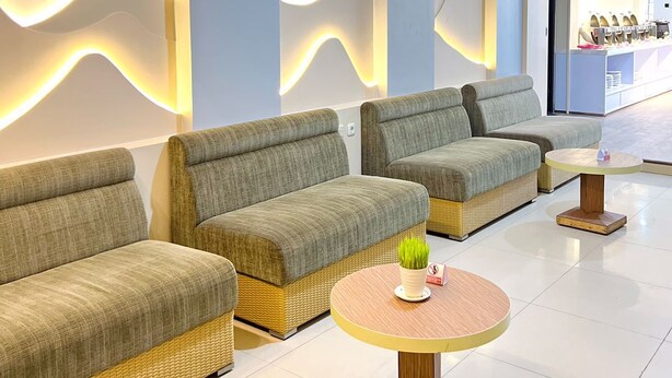 A modern lounge area with sofas and a round table, featuring a marble wall design and ambient lighting. - Belagri Hotel & Resto (Sorong)