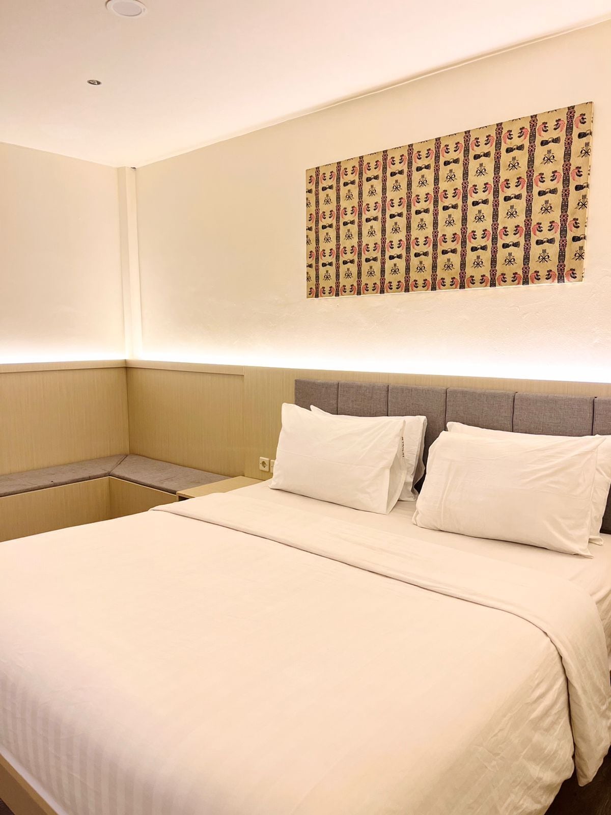 Une chambre d’hôtel avec un grand lit, une tête de lit et une œuvre d’art accrochée au mur.