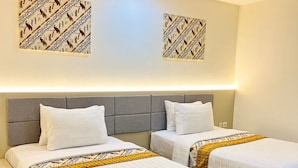 A hotel room with two beds, a grey headboard, and patterned wall art. - Belagri Hotel & Resto (Sorong)