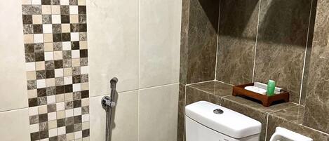 A bathroom with a toilet, a shower, and a tiled wall with a checkered pattern.