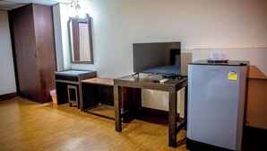 A small room with a wooden desk, a television, and a refrigerator.