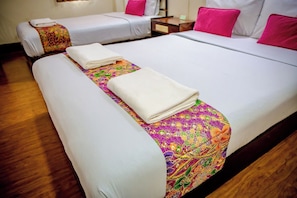 Habitación de hotel con dos camas, cada una con ropa blanca y colchas estampadas con motivos florales.