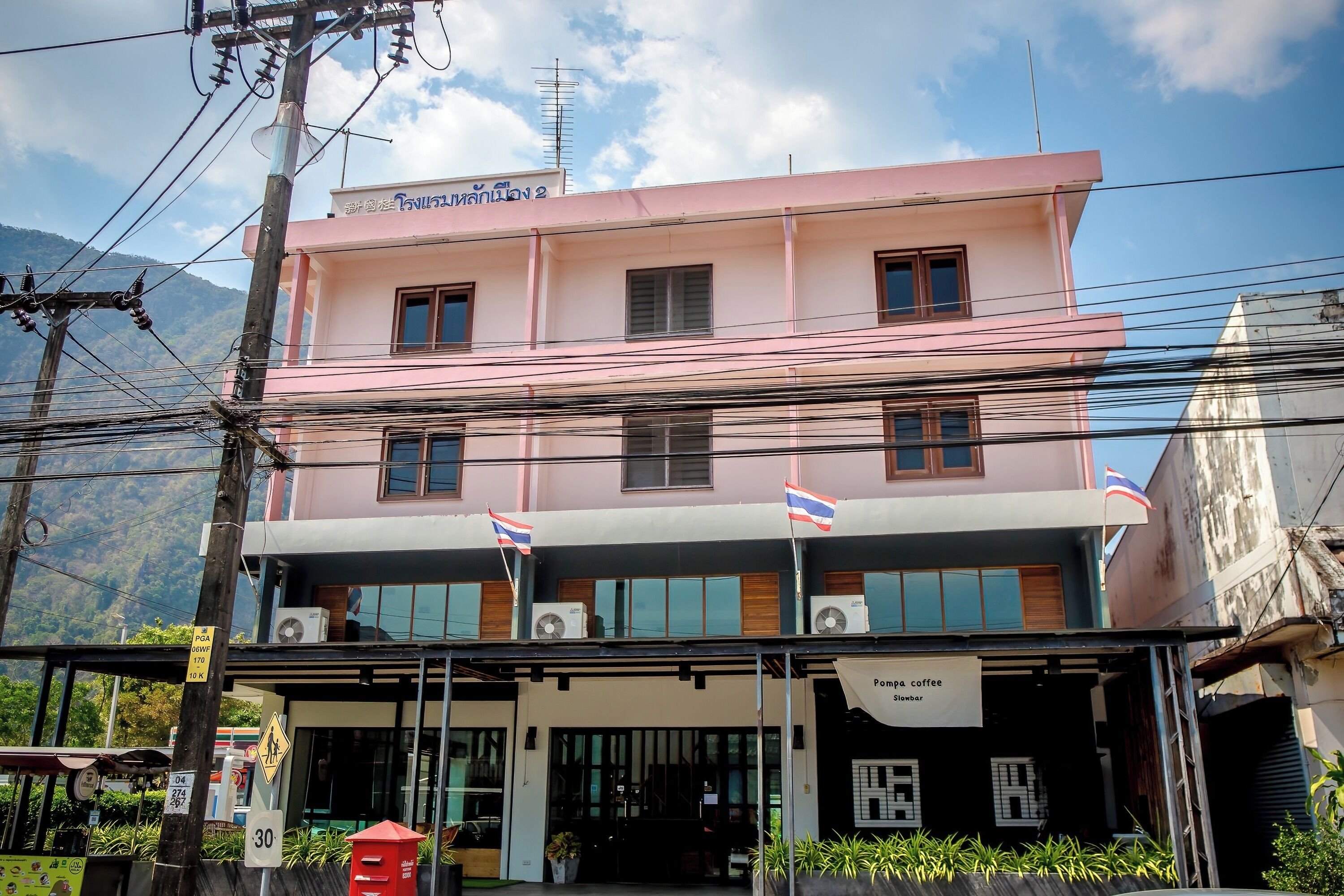 A pink building with multiple windows and flags, a sign for a coffee shop, and a visible entrance.
