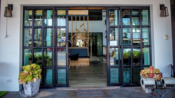 A hotel entrance with large glass doors, a welcome mat, and potted plants.