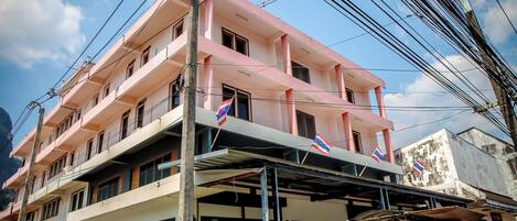 A multi-story building with balconies, a covered entrance, and flags.