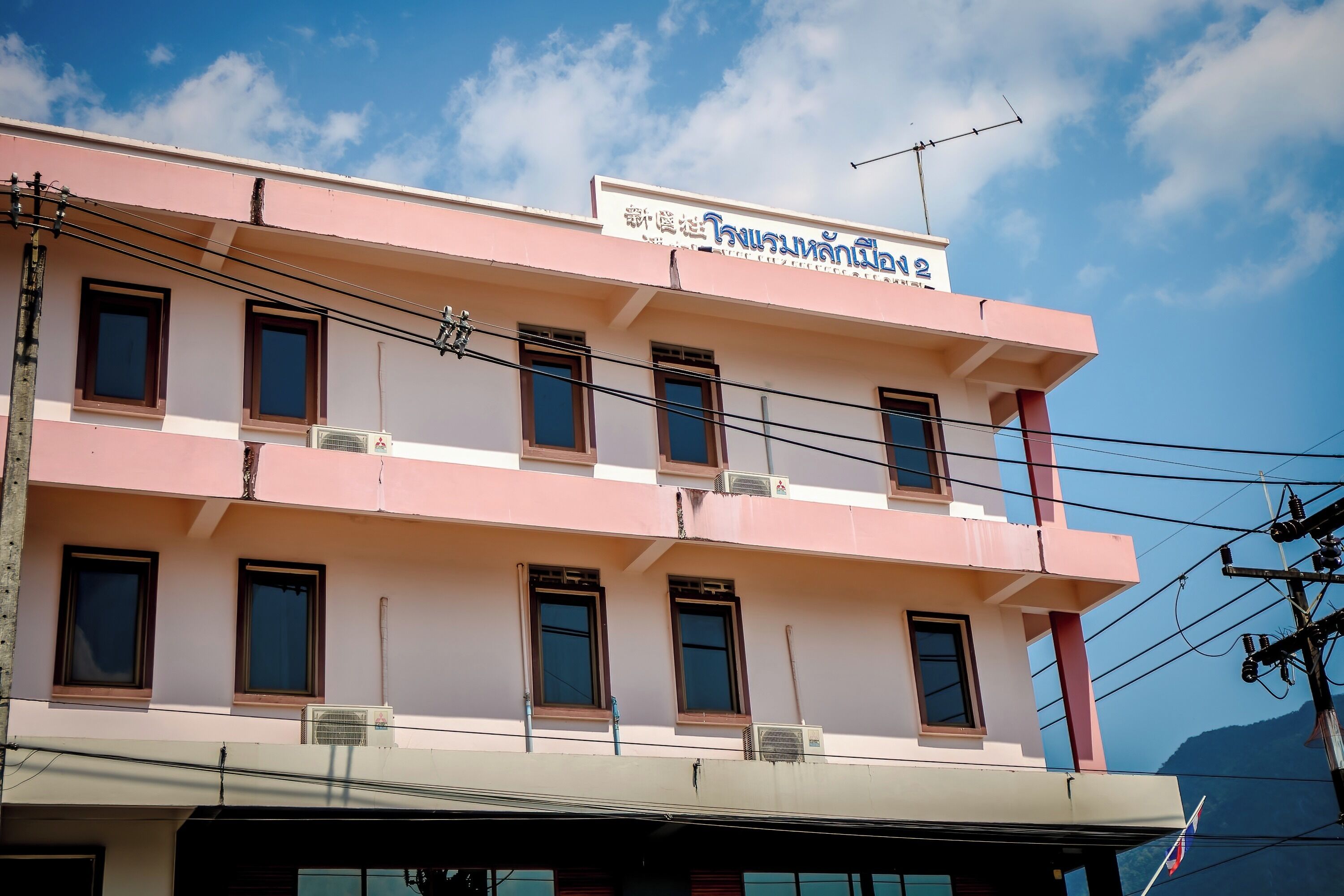 A multi-story building with a sign in a foreign language, multiple windows, and air conditioning units.