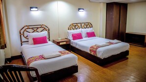 A hotel room with two beds, wooden headboards, white bedding, and pink pillows.