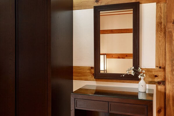 A wooden vanity with a mirror, a vase with flowers, and a glass countertop. - Hanok stay NAMWONYECHON (Namwon)