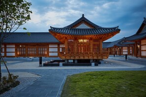 A traditional wooden building with a tiled roof, surrounded by a courtyard with stone pathways and a grassy area. - Hanok stay NAMWONYECHON  (Namwon)