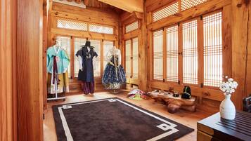 A traditional Japanese room with wooden walls and tatami flooring, featuring a tatami mat, a wooden table, and a display of traditional clothing.