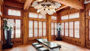 A traditional Japanese-style room with tatami flooring, a low table with cushions, and large windows with wooden lattice.