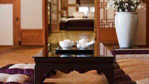 A traditional Japanese-style room with tatami flooring, a low wooden table with a tea set, and a large white vase with flowers.