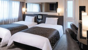 Een hotelkamer met twee bedden, een bureau, een stoel, een spiegel en een televisie.