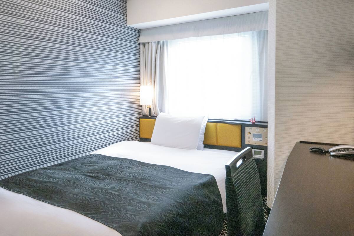 Une chambre d’hôtel avec un lit, une table de chevet et une fenêtre avec des rideaux.