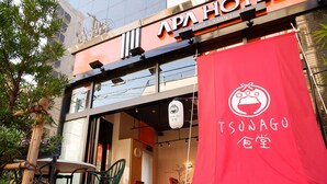 Het exterieur van een restaurant met een rode luifel waarop de naam 'TSUNAGU' staat.