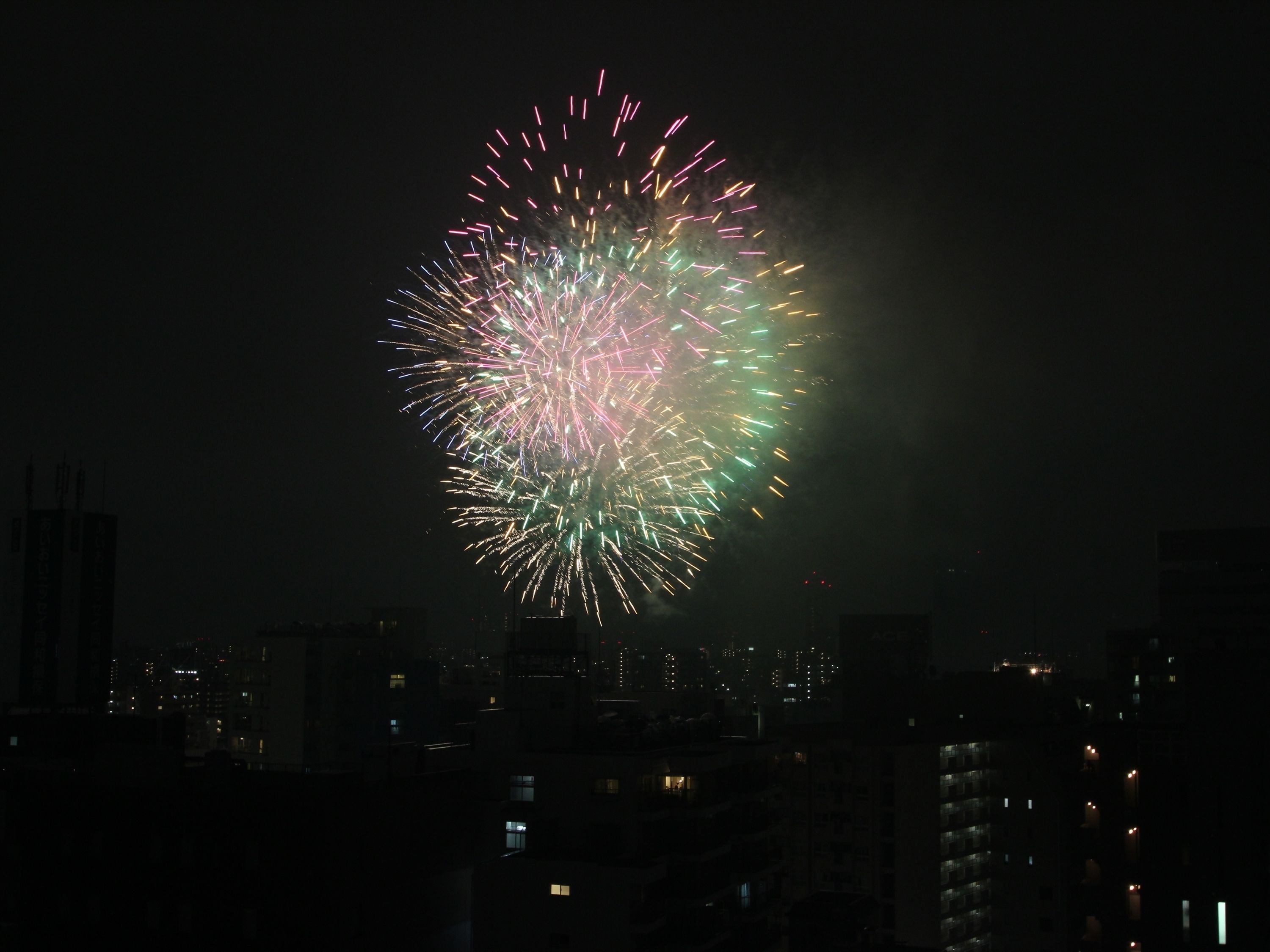 Un paisaje urbano nocturno con un gran y colorido espectáculo de fuegos artificiales en el cielo.