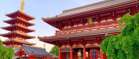 Un templo japonés tradicional con una pagoda de varios niveles y un edificio principal de paredes rojas y blancas.