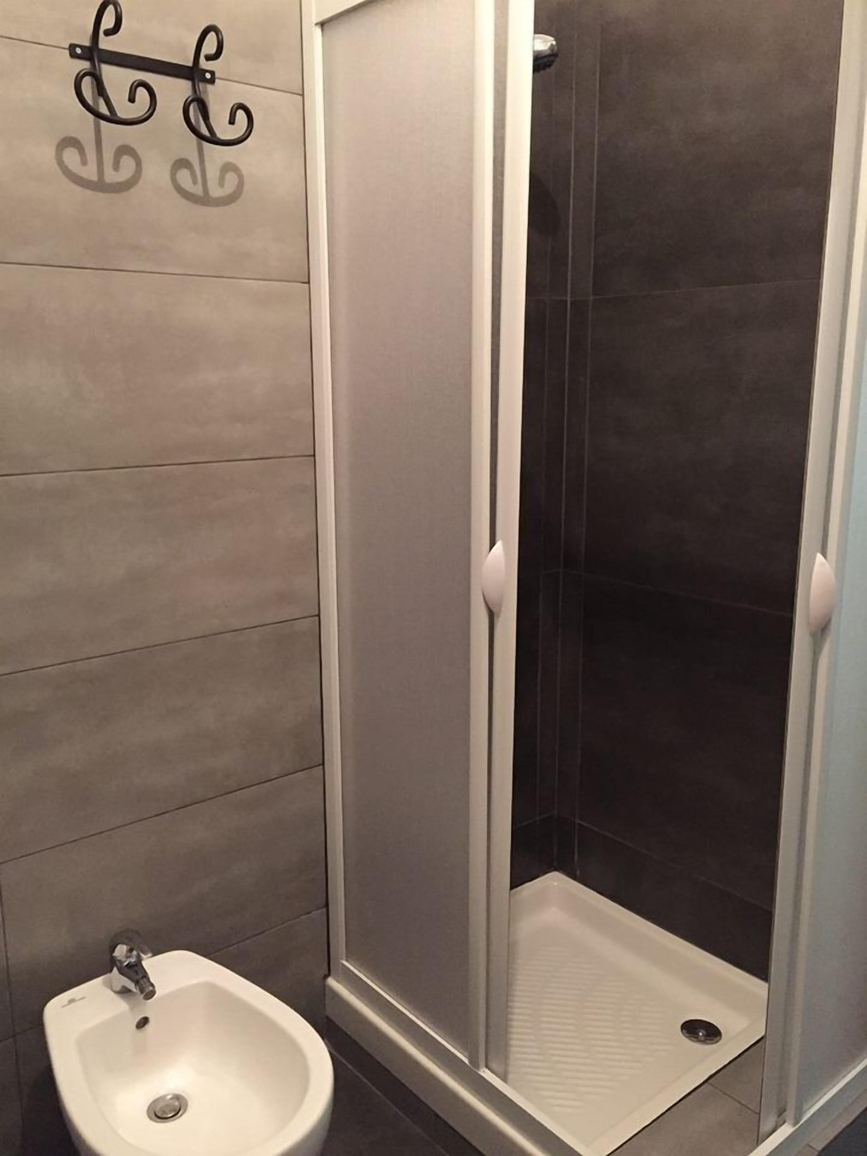 A bathroom with a shower enclosure, a bidet, and a towel rack.