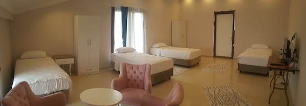 Habitación de hotel con dos camas individuales, zona de estar con una silla, una mesita y un armario.