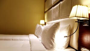 Une chambre d’hôtel avec un lit bien fait, une tête de lit dotée d’une lampe et une table de chevet fixée au mur.