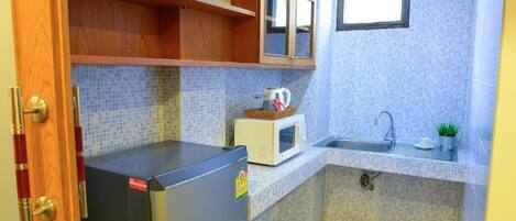 A compact kitchen with a refrigerator, microwave, sink, and wooden cabinets.