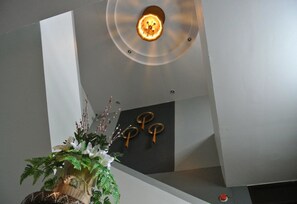 Un intérieur moderne agrémenté d’un luminaire au plafond, d’un élément décoratif fixé au mur et d’une plante en pot.