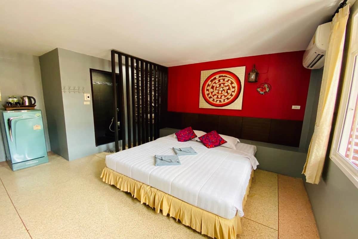 Een hotelkamer met een bed, een kledingkast, een kleine kitchenette en een rode muur met een rond ontwerp.