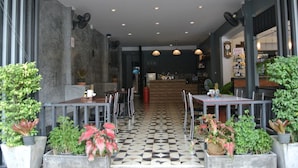 A restaurant with a checkered floor, tables, chairs, and potted plants.