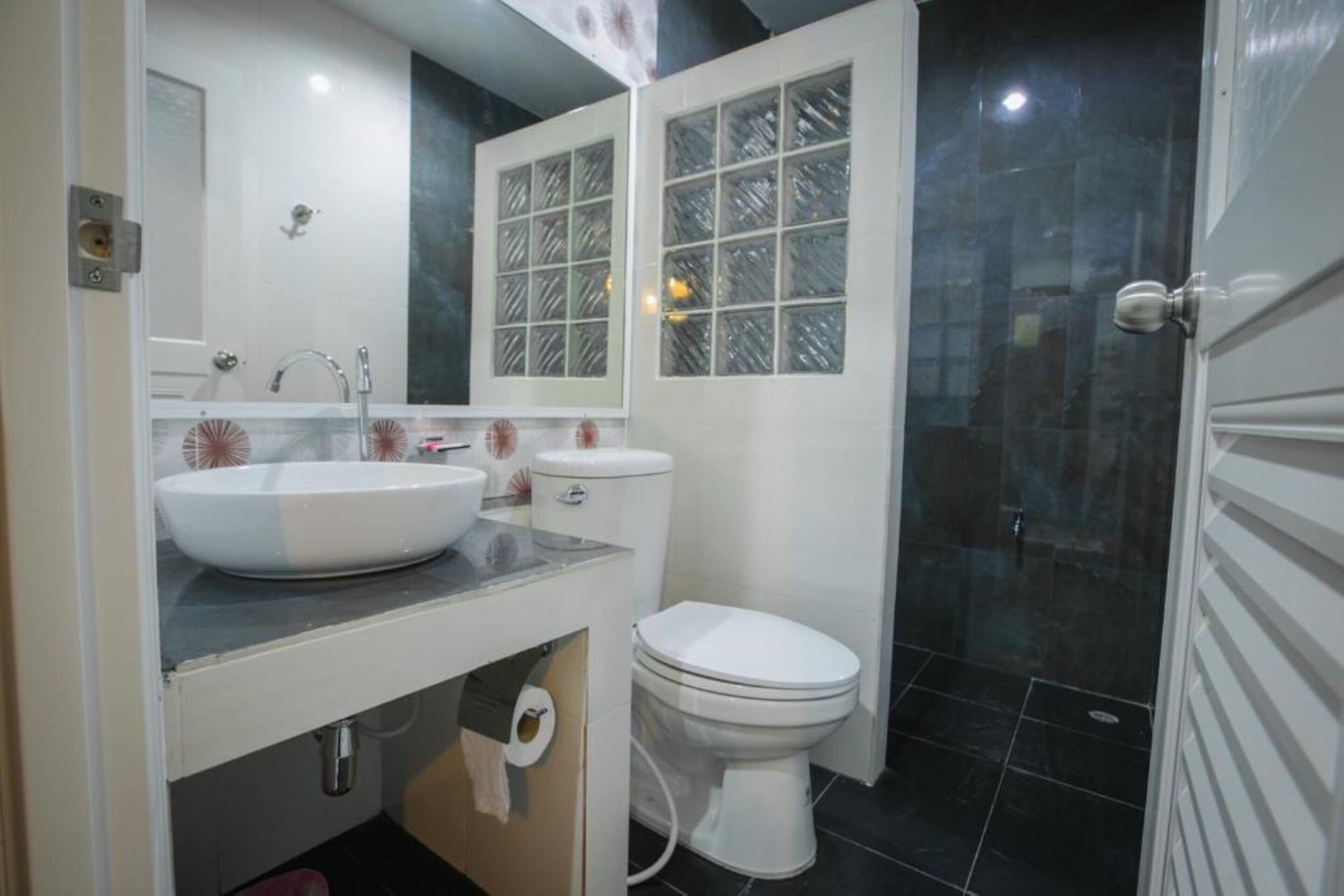 A bathroom with a white sink, toilet, and a glass shower enclosure.