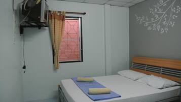 Uma cama de solteiro com cabeceira de madeira, janela com cortina e parede com design floral.