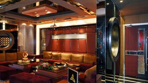 Un lobby de hotel lujoso con un sofá tapizado rojo, una mesa de centro de madera y un espejo grande.