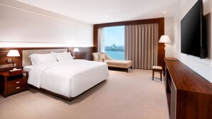 Una habitación de hotel moderna con una cama grande, un escritorio, una silla y un televisor.