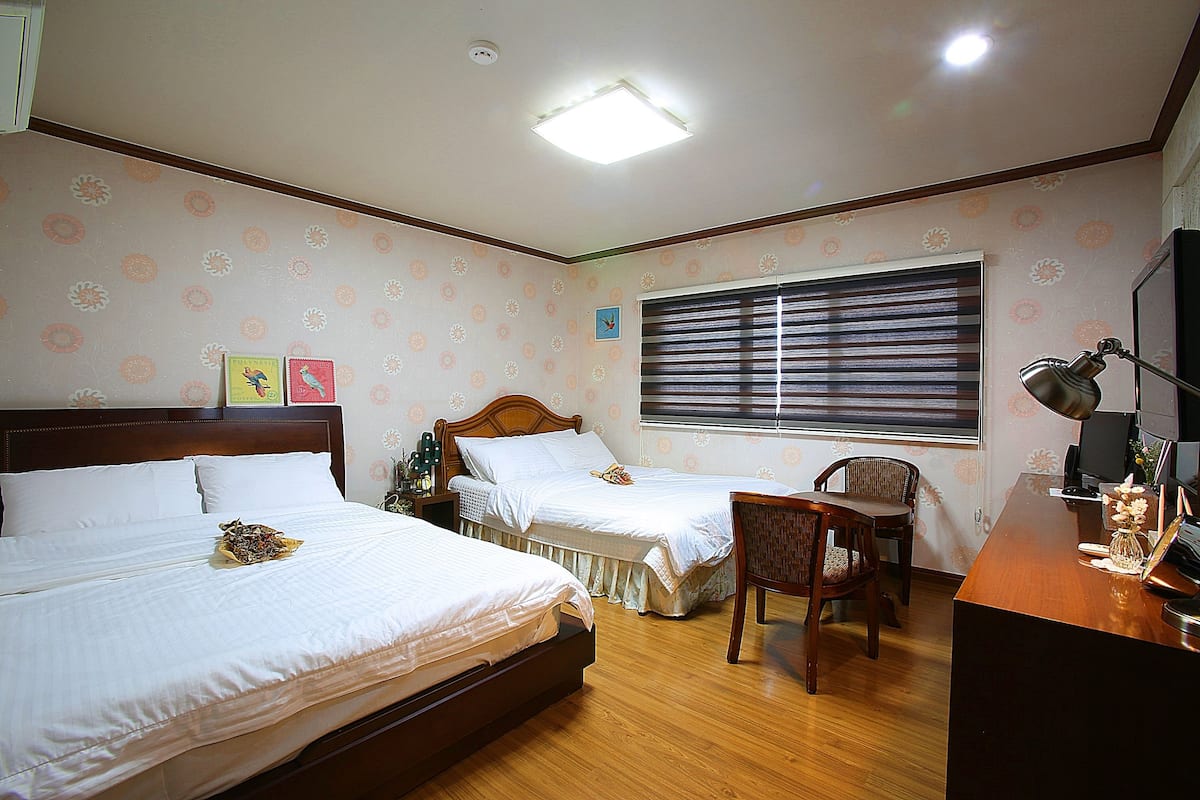 A hotel room with two beds, a desk, and a chair.