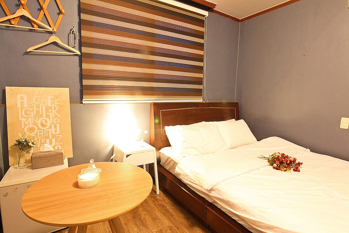 A hotel room with a bed, bedside table, lamp, and a wall-mounted artwork.