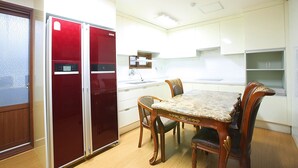 A compact kitchen with a dining table and chairs, a refrigerator, and a sink. - Woosung Hotel (Seogwipo)
