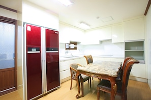 Enjoy meals in this cozy kitchen with a dining table for two, featuring a refrigerator, oven, and microwave.