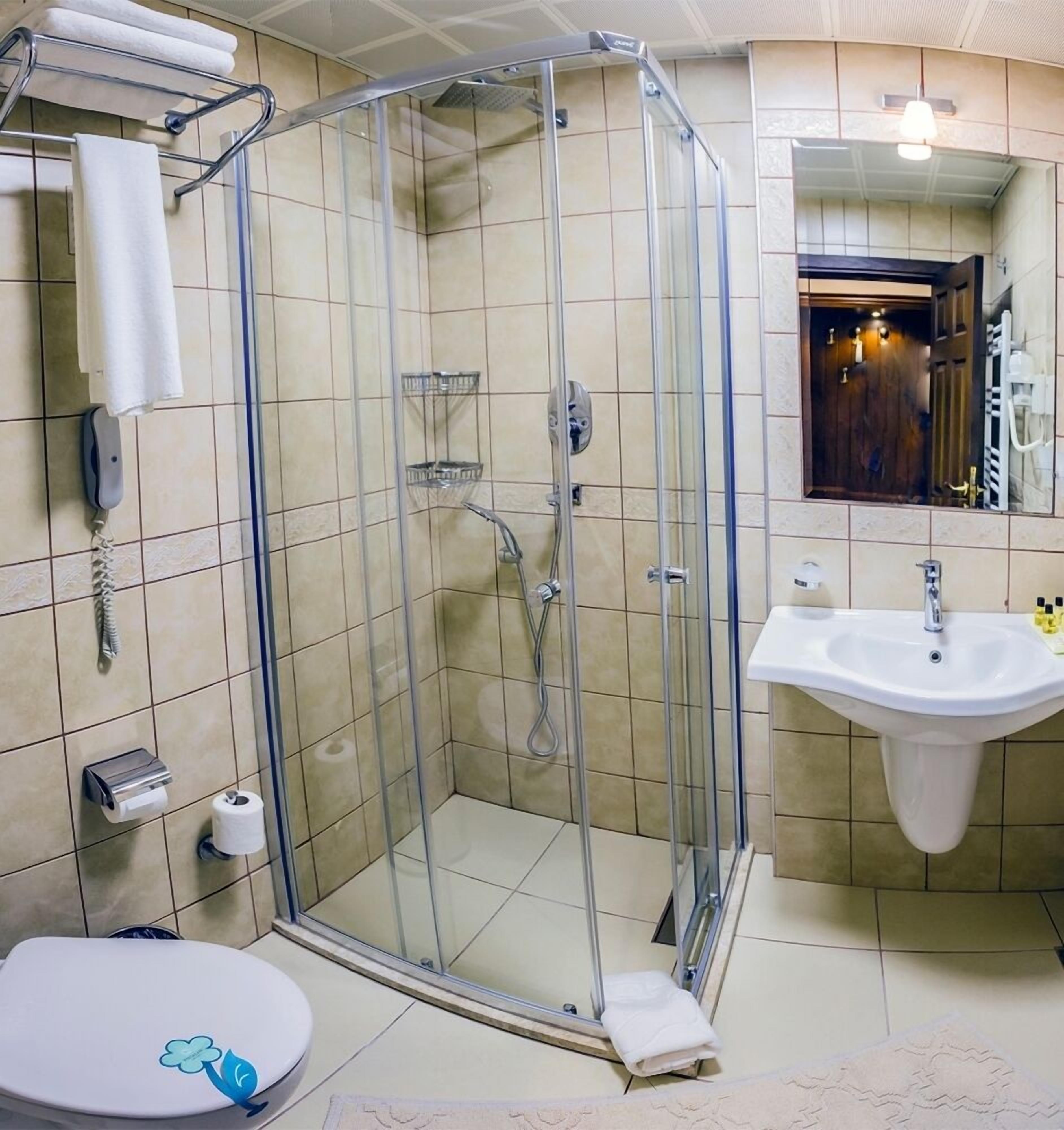 Un baño con ducha envuelta en vidrio, inodoro, lavabo y espejo.