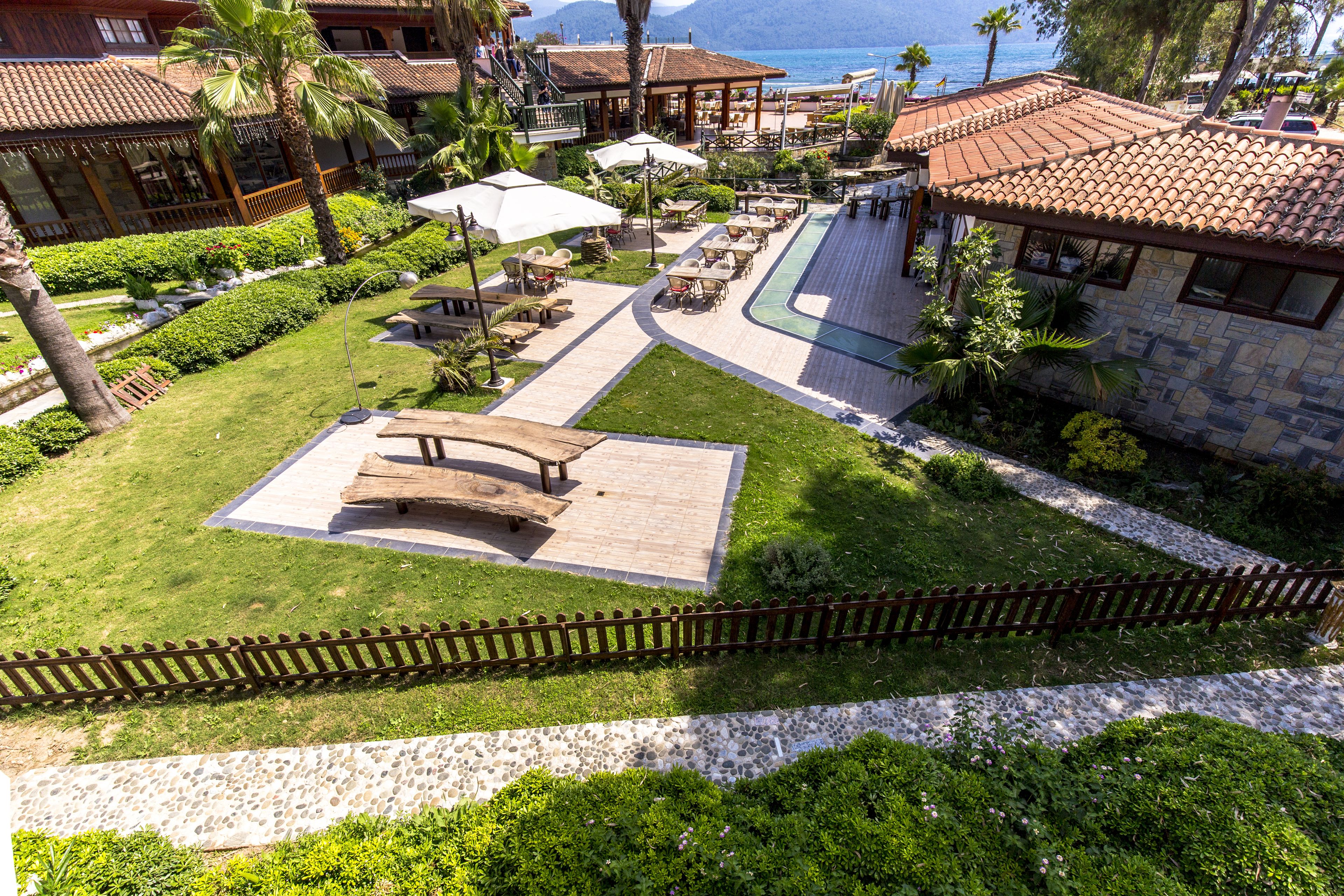 Vista aérea de un complejo turístico con zonas de estar al aire libre, piscina y vista al mar.