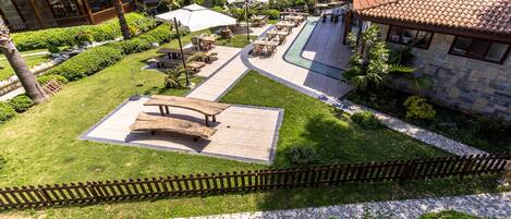 Vista aérea de un complejo turístico con zonas de estar al aire libre, piscina y vista al mar.