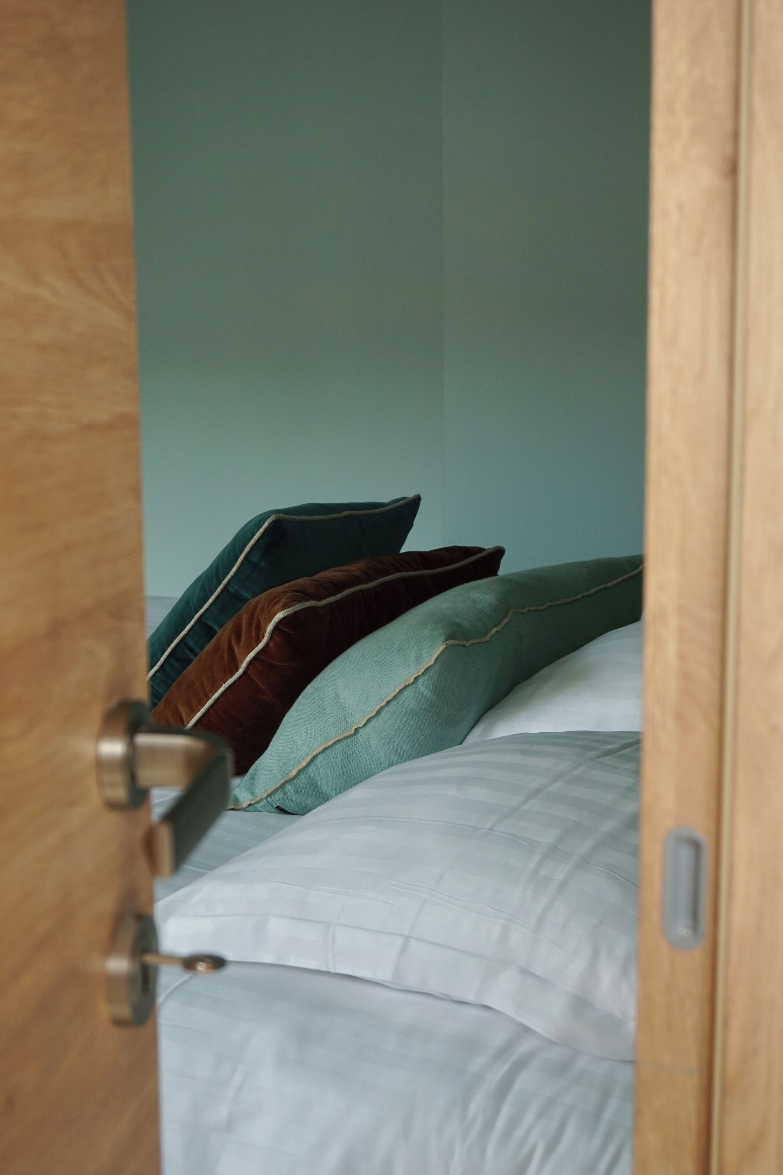 A bedroom with a bed, pillows, and a wooden door.