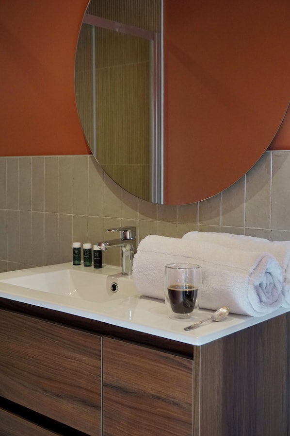 A bathroom with a white sink, a round mirror, and a towel. - Hôtel les Bains (Saint-Valery-en-Caux)